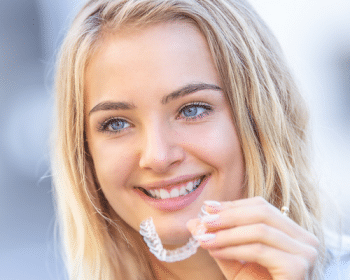 young teenager smiling while holding her new Invisalign in Saginaw, TX.